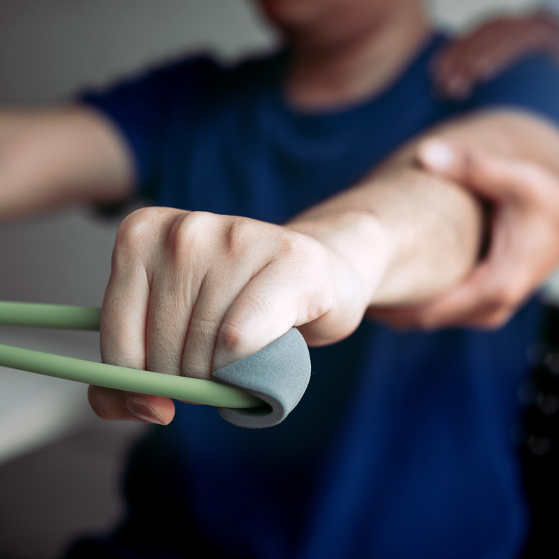 Man is stretching bands during physical rehabilitation at Boro Chiropractic Care.